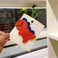 Handmade knitted orange and blue dinosaur hair clip on white card display - Orange Dinosaur