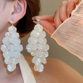 Gros plan sur de longues boucles d'oreilles à pétales nacrés portées par un mannequin - Gland de pétale blanc doré (105#)