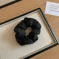Close-up of black knitted hair scrunchie with woven texture on a beige linen tray - Knitted Scrunchie / Black