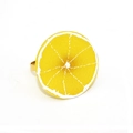 Vue détaillée du rond de serviette citron 3D avec support doré sur tissu blanc - Tranche de citron