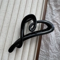 Detailed macro view of a glossy black heart-shaped hair claw clip on a velvet tray - Bright Black