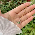 Detail of 18K gold plated necklace featuring a green bow pendant and beaded accents - Green