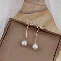 Dettaglio di orecchini a fiocco dorati con cristalli bianchi e perle eleganti - Oro Fiocco Perla