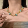 Vintage-Goldhalskette mit türkisfarbenen ovalen Edelsteinen auf Modellporträt - Blau
