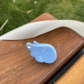 Détail d'une pince à cheveux bleue en forme d'aile avec strass sur fond bois - Bleu ciel