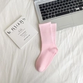 Pink ribbed cotton crew socks in a cozy lifestyle setting on white bedding - Light Pink