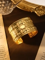 Nahaufnahme des breiten goldenen Bohemian-Armreifs mit Vintage-Relief und glänzendem Zentrum - Oval Blumen Gold