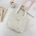 Top view of cream quilted tote bag featuring colorful heart embroidery and logo patch. - Multicolor Gourd Heart