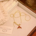 Close-up of vintage gold fishtail pendant necklace with red enamel and pearl detail - Red