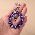 Detailed view of Evil Eye keychain featuring a blue eye bead and crystal palm charm in hand - Silver Evil Eye