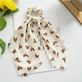 Detail of beige satin hair scrunchie with brown leaf pattern on lifestyle background - White Leaf
