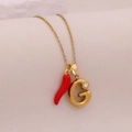 Macro detail of gold chili pepper and crystal-encrusted letter G pendant on necklace - Letter G(G)