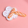Vue macro de deux mini baguettes en résine sur une assiette nuage rose à pois - Baguette au Chocolat Noir et Blanc / Grande Taille (3.8cm*1.0cm)