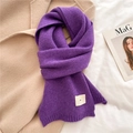 Detailed close-up of purple knitted winter scarf with a small beige woven ERD label - Purple