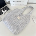 Detail of blue and white checkered canvas tote bag with woven label on a white desk - White Checkered