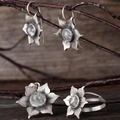 Vue détaillée d'une parure en argent floral avec pierres sur fond de bois rustique - Parure de bijoux (Boucles d'oreilles+Bague+Pendentif) / Blanc