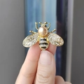 Golden bee brooch with white rhinestones and a champagne pearl shown in hand for size - Bee-Champagne Pearl (XZ0191)