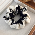 Détail d'un chouchou en dentelle florale noir et beige sur un plateau à bijoux - Noir Beige Style Broderie Épissée