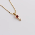 Detail of gold-plated key necklace featuring a red heart crystal and white zircon stones - Dark Red