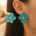 Vibrant teal flower stud earrings with golden centers shown worn on a model - Teal Flower Earrings with Gold Stamens (11414)