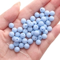 Matte light blue acrylic round beads held in hand for DIY jewelry making accessories - Sky Blue