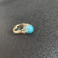 Detailed view of handmade gold wire-wrapped ring with a round blue natural stone - Adjustable Open / Grey Stone