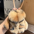 Close-up of fluffy tiger print faux fur bag charm with a premium brown leather strap - Leopard Print