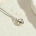 Close-up van hartvormige hanger met gepolijste zilveren finish op een stenen textuur - Mini (1.0cm) / Zilver