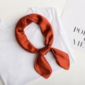 Vibrant orange silk satin square scarf tied in a knot on a white t-shirt top - Brick Red