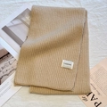 Thick khaki beige knitted rib scarf with brand label on a soft aesthetic background - Milk Apricot