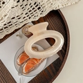 Macro detail of large beige acrylic hair claw clip with France Handmade text on wood - Yellow