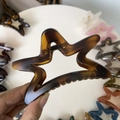 Macro detail of amber star-shaped hair claw clip with cutout hollow design and tortoise finish - 11cm / Matte Light Tortoise