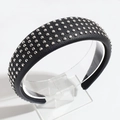 Close-up of black PU leather headband with silver round metal rivets on a display stand - Black