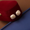 Macro shot of geometric square pearl stud earrings resting on a red velvet jewelry box - 14mm / 14mm Champagne