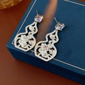 Detalle de los pendientes de plata con circonitas y diseño calado sobre caja de joyas - Plateado