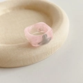 Macro shot of pink resin square ring featuring metallic Saturn orb detail on textured tray - Pink Planet Style