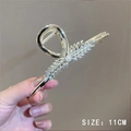 Pince à cheveux 11cm dorée avec strass et perle tenue par une personne - 106# Épi de Blé Doré