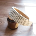 Detail view of woven raffia headband in beige and grey on a vintage glass bottle - Grey and White Interwoven