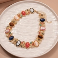 Nahaufnahme der goldenen Vintage-Halskette mit Cameo-Porträts und bunten Kristallblumen - Cameo Porträt Blume Halskette