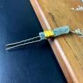 Macro shot of green crystal slice hair pin with gold wire wrapping on wood surface - Prehnite