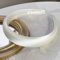 Close-up of pearl white satin sponge headband on a gold mirror with textured paper - Milk White