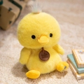 Plush yellow duck toy with rainbow hair detail and brand tag on soft carpet - Sitting Duck