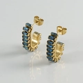 Detalle de pendientes de aro dorados con circonitas azules sobre fondo blanco - Dorado Con Circonita Azul