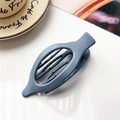 Detail view of a grey matte oval hair claw clip with cutout design on a white desk - Matte Gray Blue