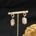 Elegant gold baroque pearl drop earrings with iridescent pink sheen on a black display - Hollow Rhombus Purple Square Baroque Studs