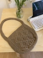 Dettaglio borsa in maglia marrone con trama a rombi 3D su una scrivania in legno rustico - Con Bottone / Cachi
