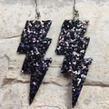 Macro view of black glitter lightning bolt earrings with holographic leather texture - Black Sequin
