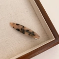 Handmade tortoiseshell acetate hair clip with gold logo in a wooden tray - Amber