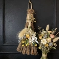 Detail of decorative holiday broom with dried flowers, twine, and metal witch charm - Broom+Flowers+Witch