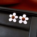 Close-up of five-petal silver flower studs with brown gemstone inlay on leather - Silver Five-Petal Flower Gemstone Earrings